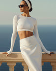 Woman in a white outfit standing on a balcony with a scenic background