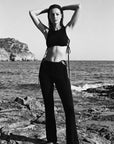 Person standing on rocky beach with ocean and cliffs in the background